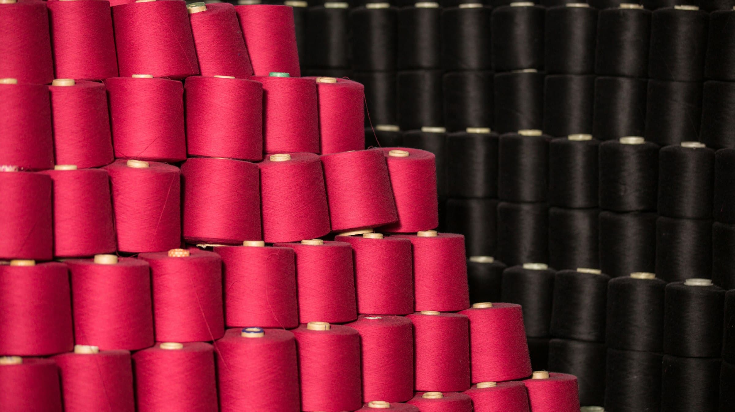 Stacks of red and black thread cones in a textile factory