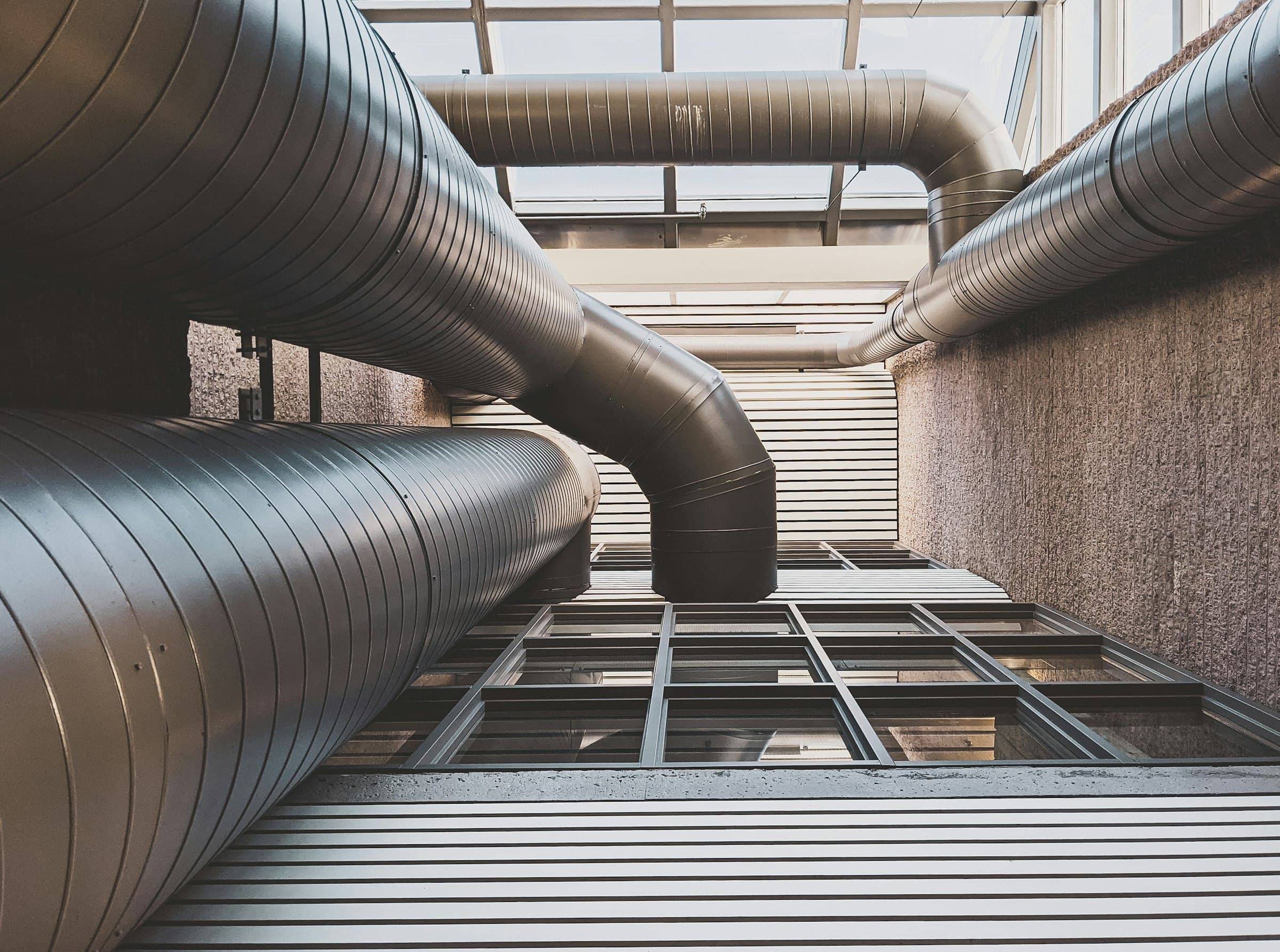 Large metal air ducts curving down the walls of a building's courtyard