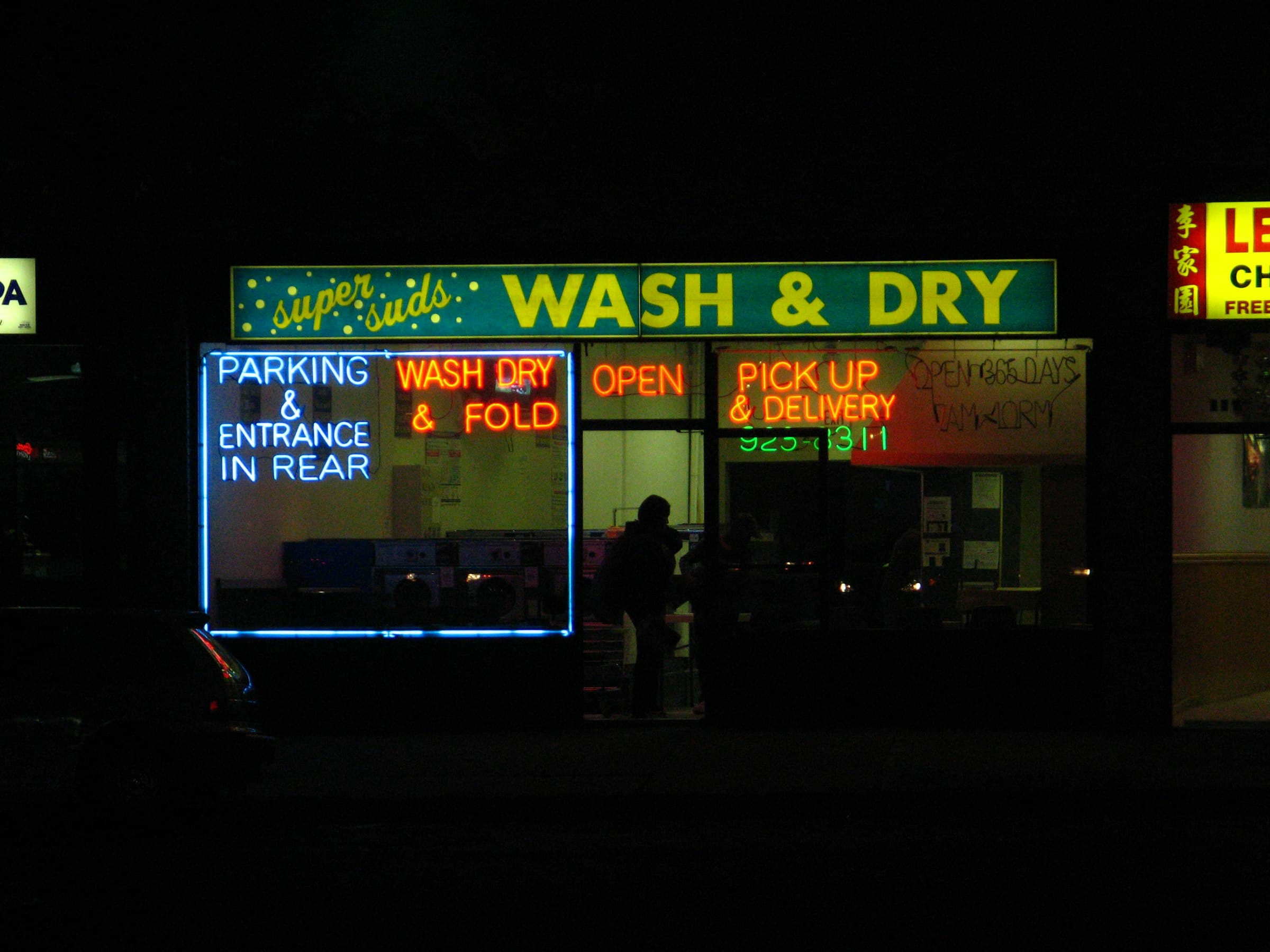 A laundromat's neon WASH & DRY sign and lit windows at night