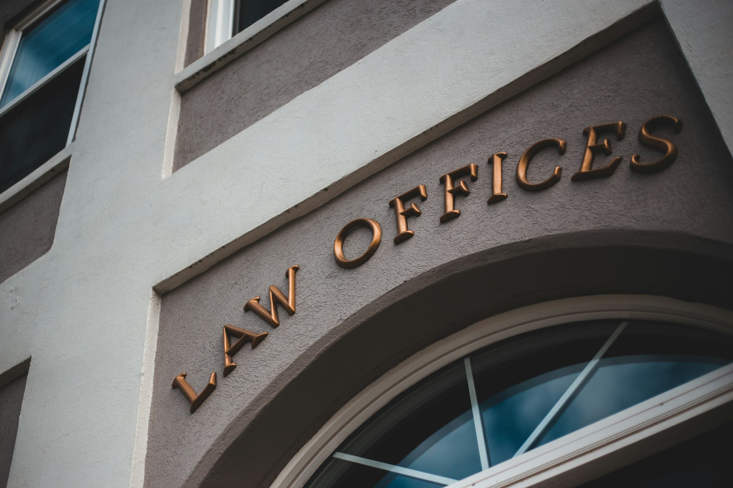 Bronze letters reading Law Offices arched over a fan window on a grey stucco building
