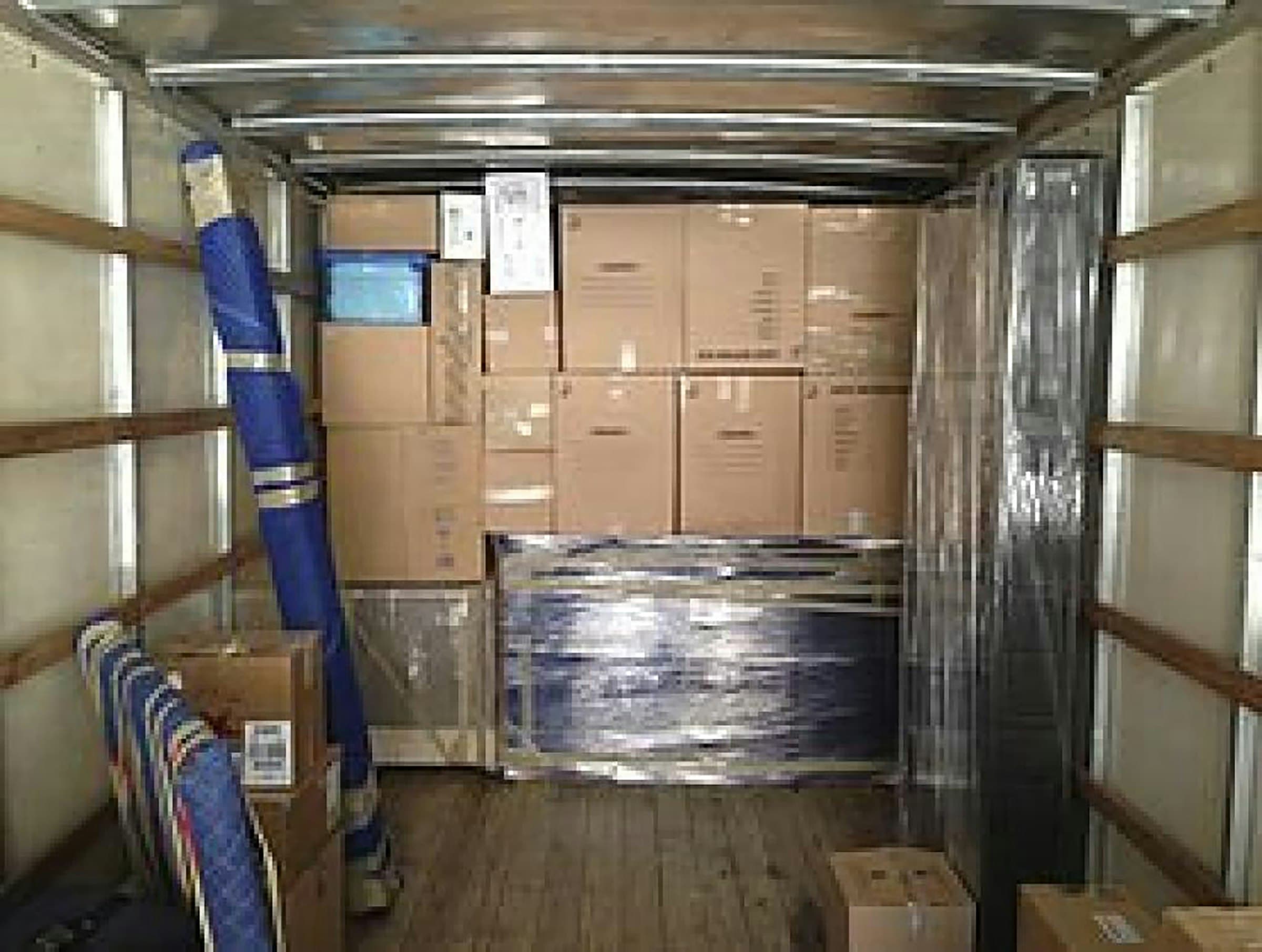 The inside of a moving truck packed with boxes and wrapped furniture