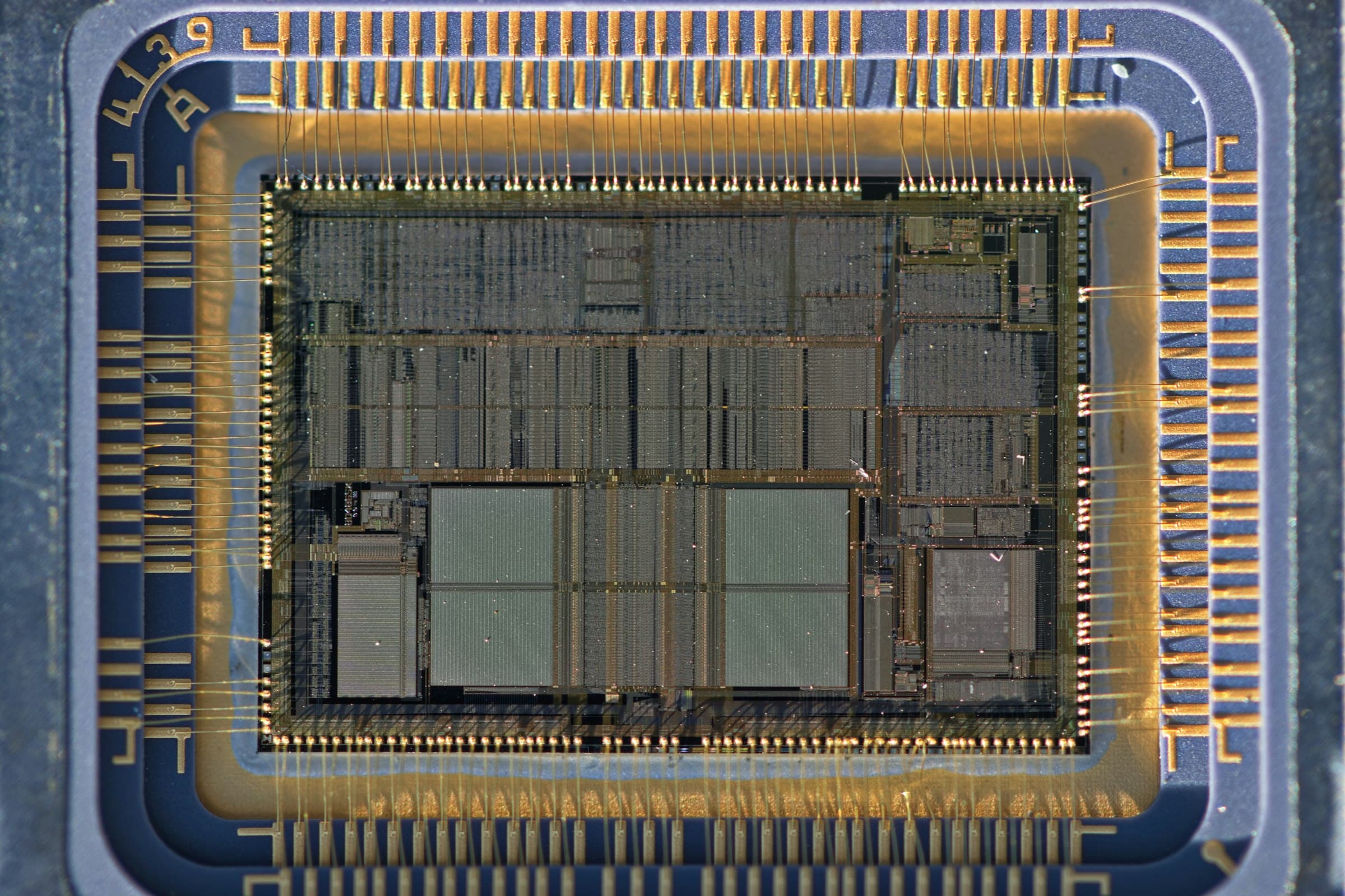 A processor with its lid off under a macro lens, the silicon die wired to its gold contacts by hair-thin bond wires