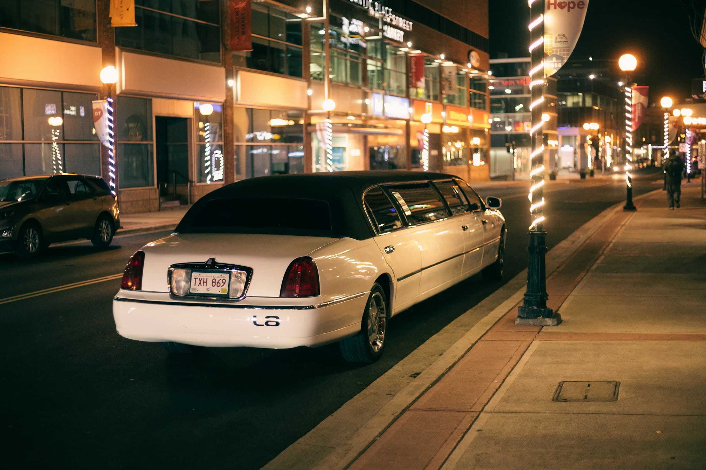 A white stretch limousine parked on a lit city street at night