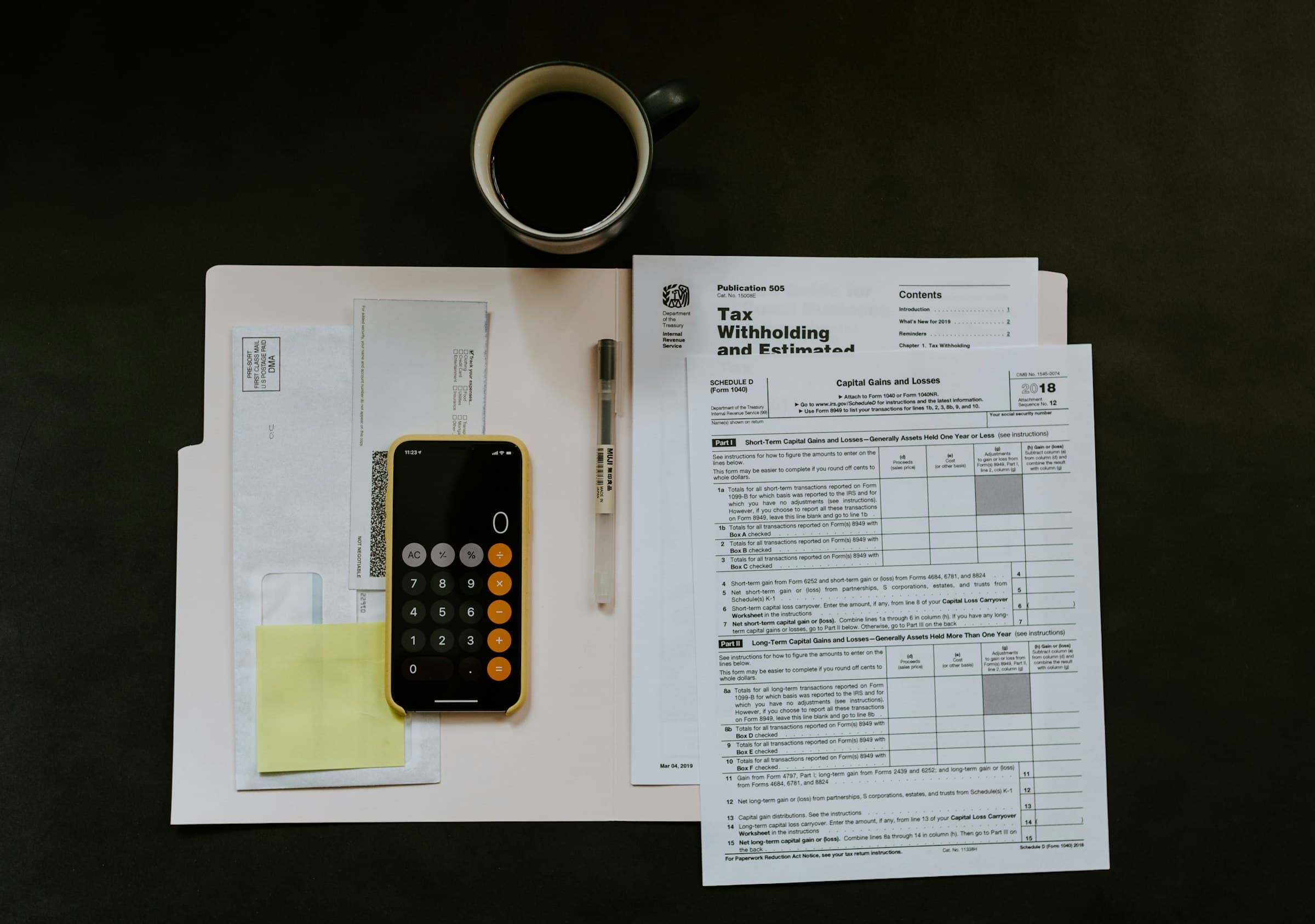 Tax forms, a calculator and a cup of coffee on a dark desk