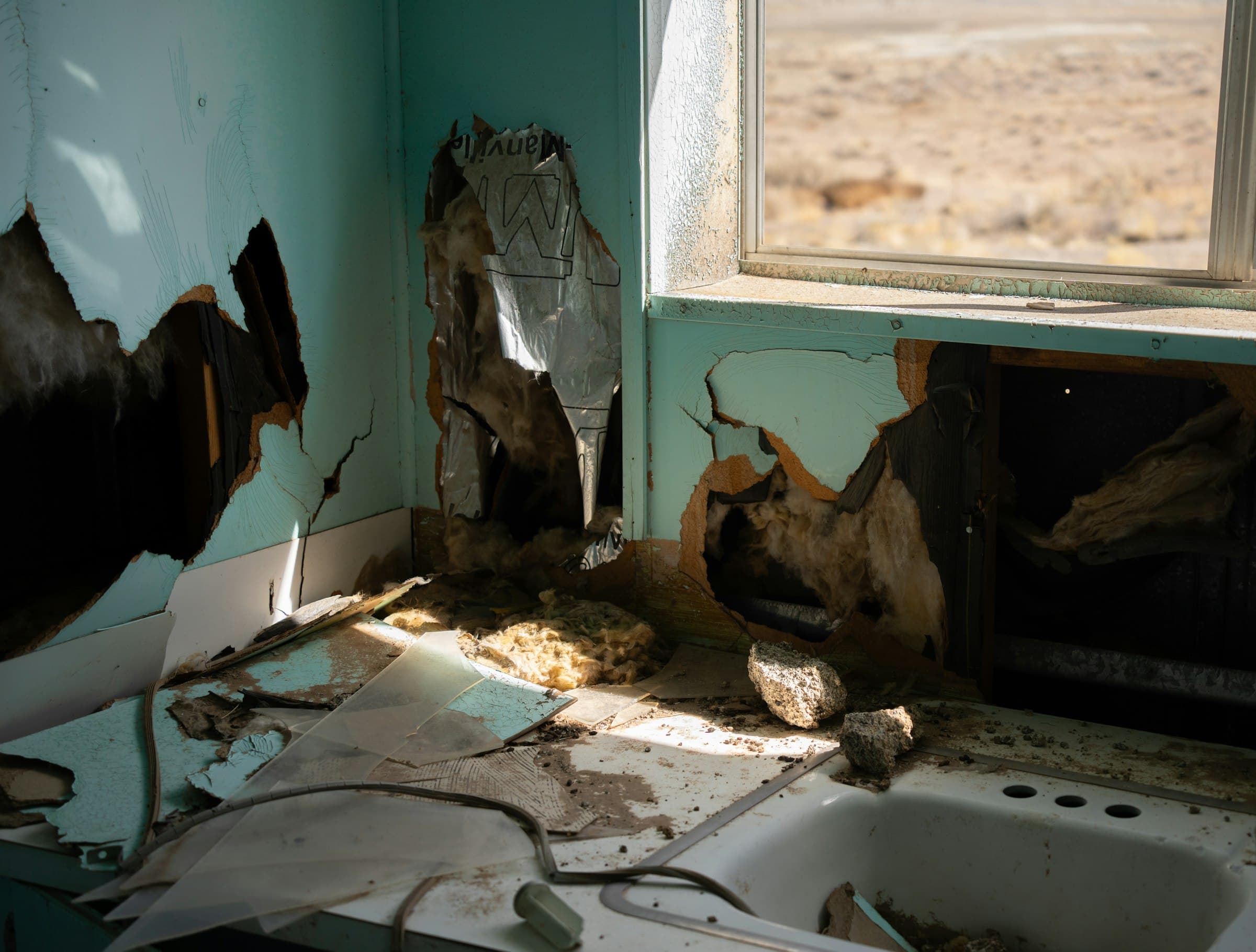A room with drywall torn open and paint peeling after water damage